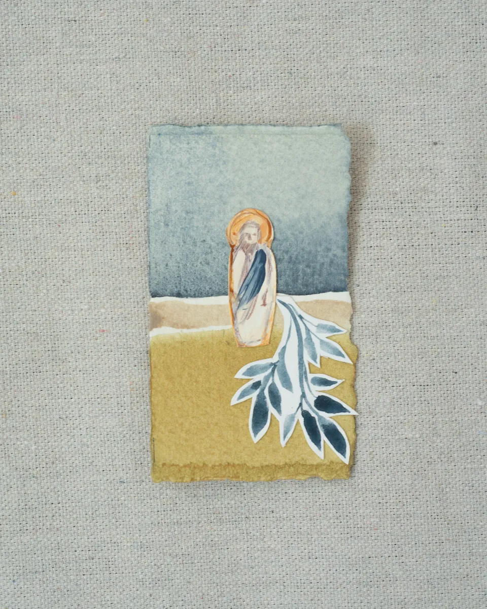 A small painting on torn-edged paper, laid on linen: a figure of Christ with a gold halo and a blue robe on a mustard field under a slate blue sky, with a cut-paper indigo branch at his feet.