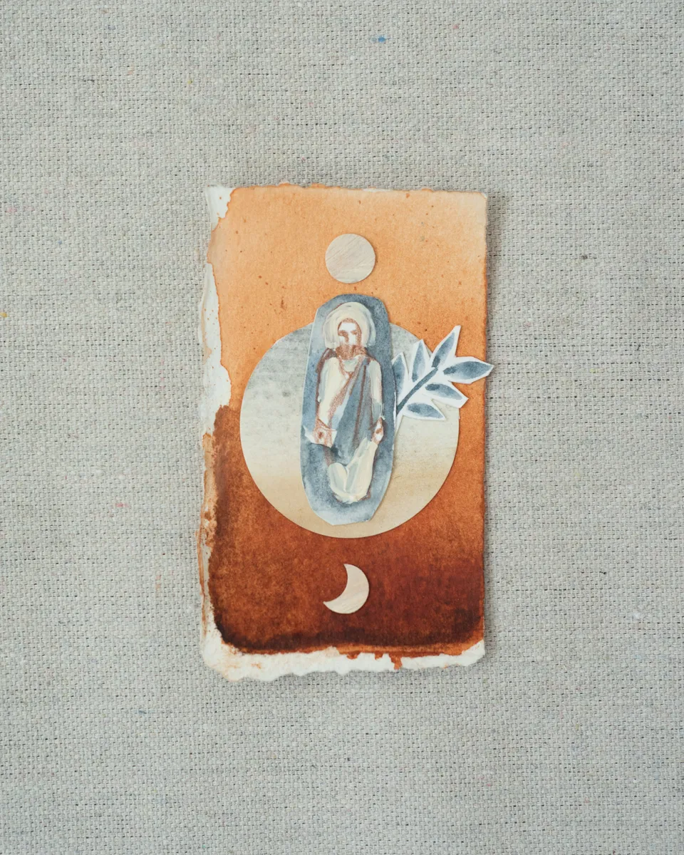 A small painting on torn-edged paper, laid on linen: a figure of Christ in a blue oval against a pale circle on burnt orange, with a full moon above, a crescent below and a cut-paper sprig of blue leaves.