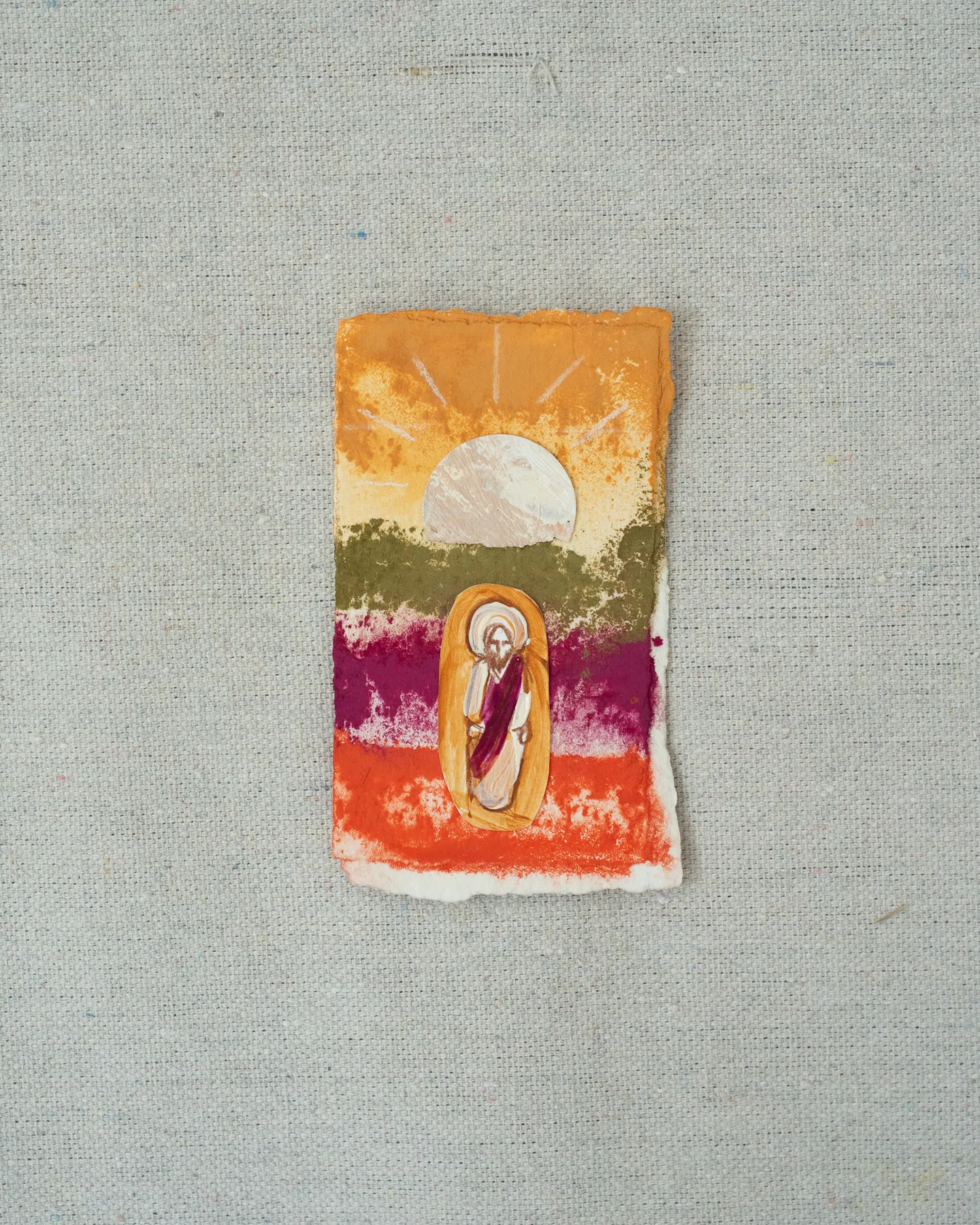 A small painting on torn-edged paper, laid on linen: a pale sun rising with painted rays over bands of orange, olive, magenta and red, and a figure of Christ in a red robe inside a golden oval.