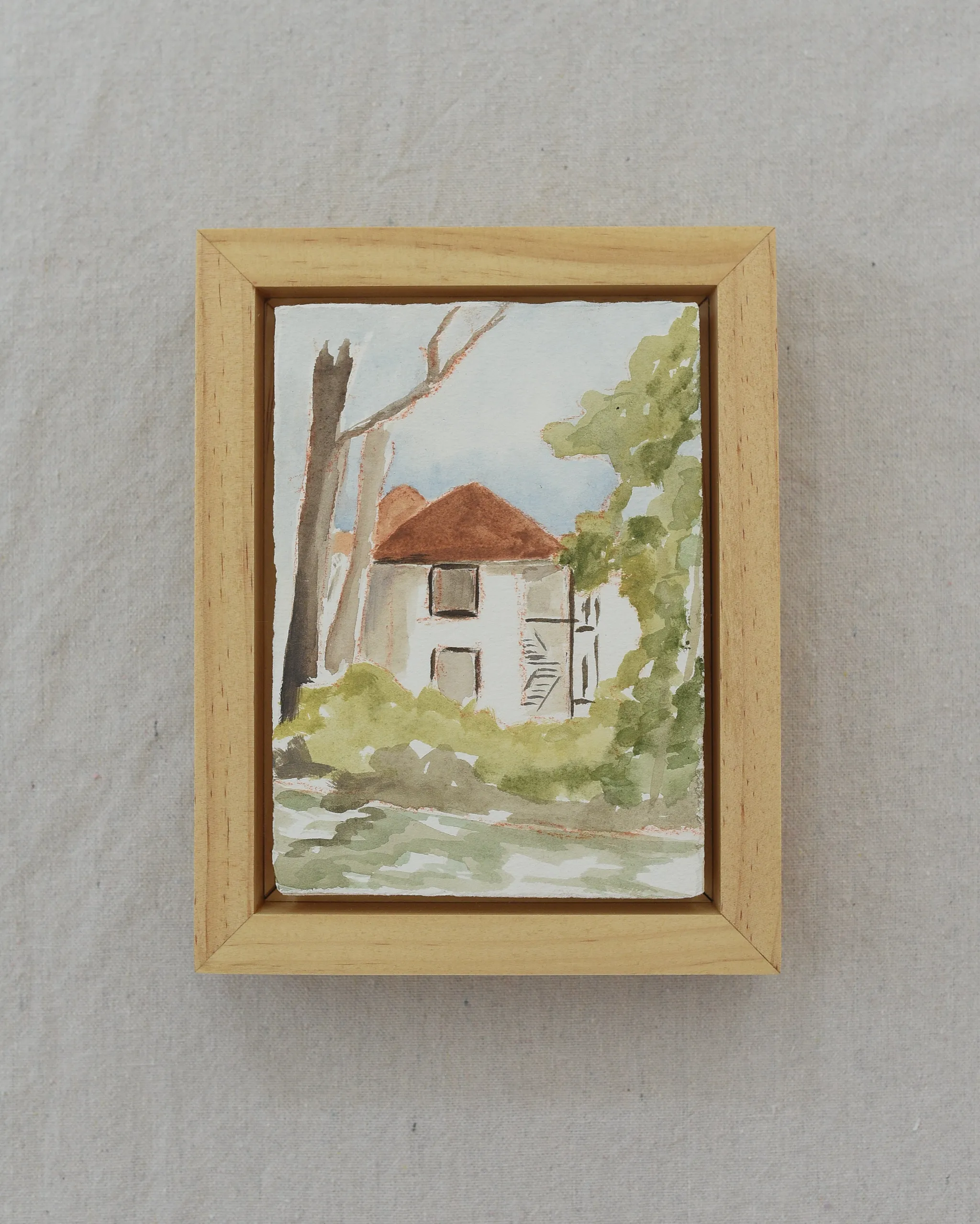 A charming house on the river, surrounded by trees in bright, light tones reminiscent of classic watercolor techniques.