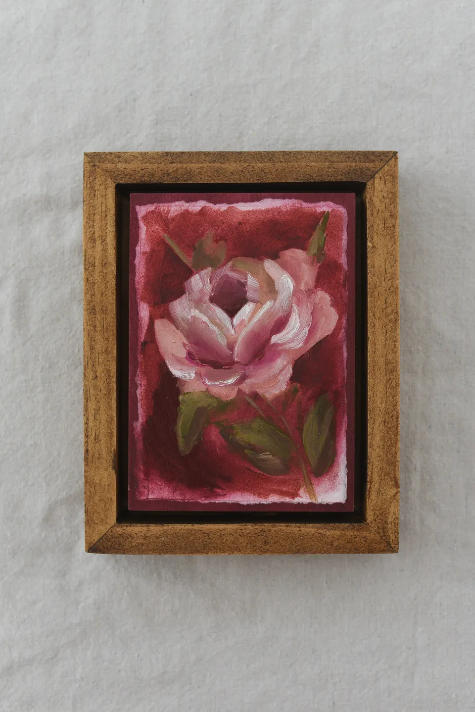 A rose blooms against a deep magenta background, rendered in acrylic and oil on paper.