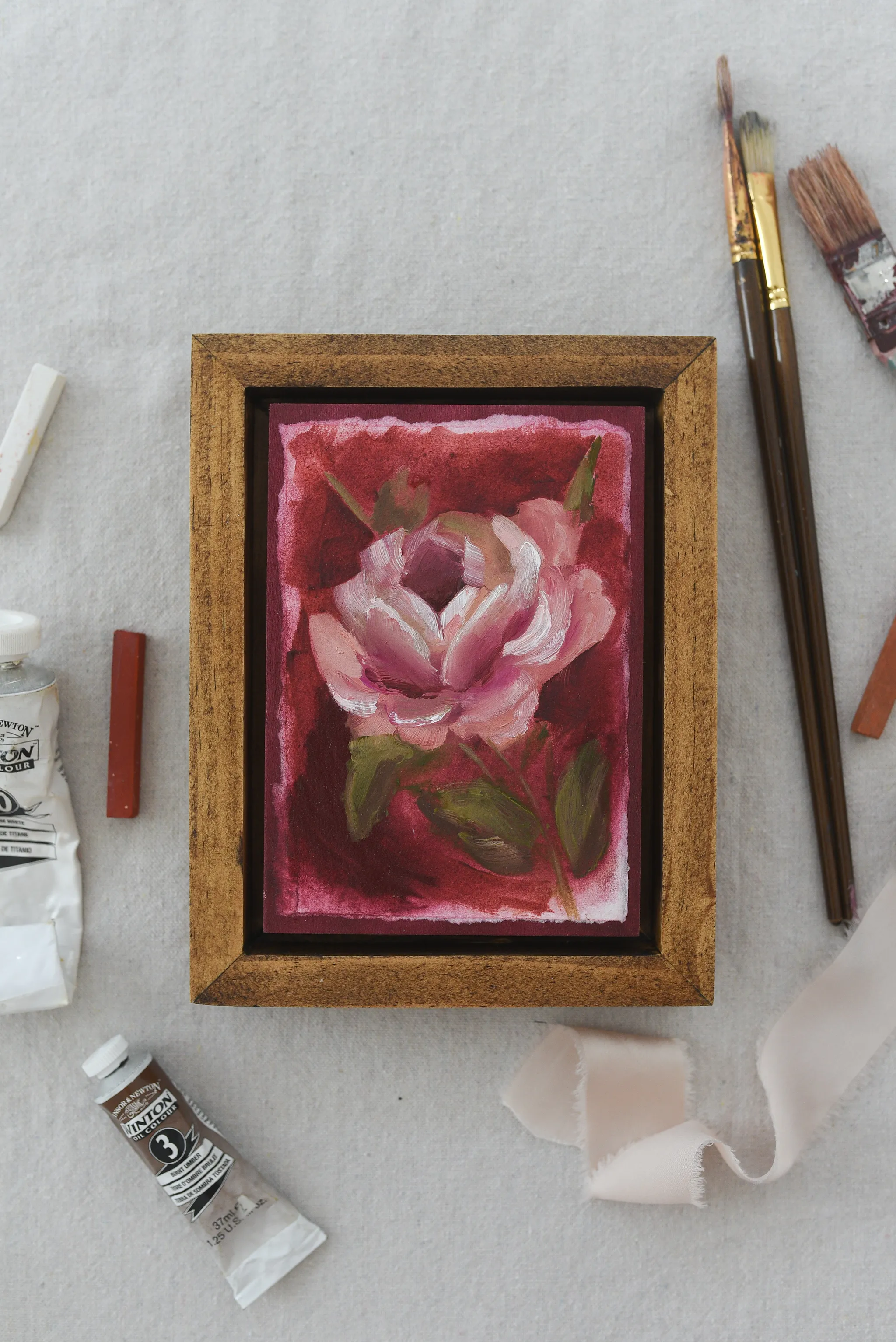 Elegant Bloom, view 3 of 9: A rose blooms against a deep magenta background, rendered in acrylic and oil on paper.