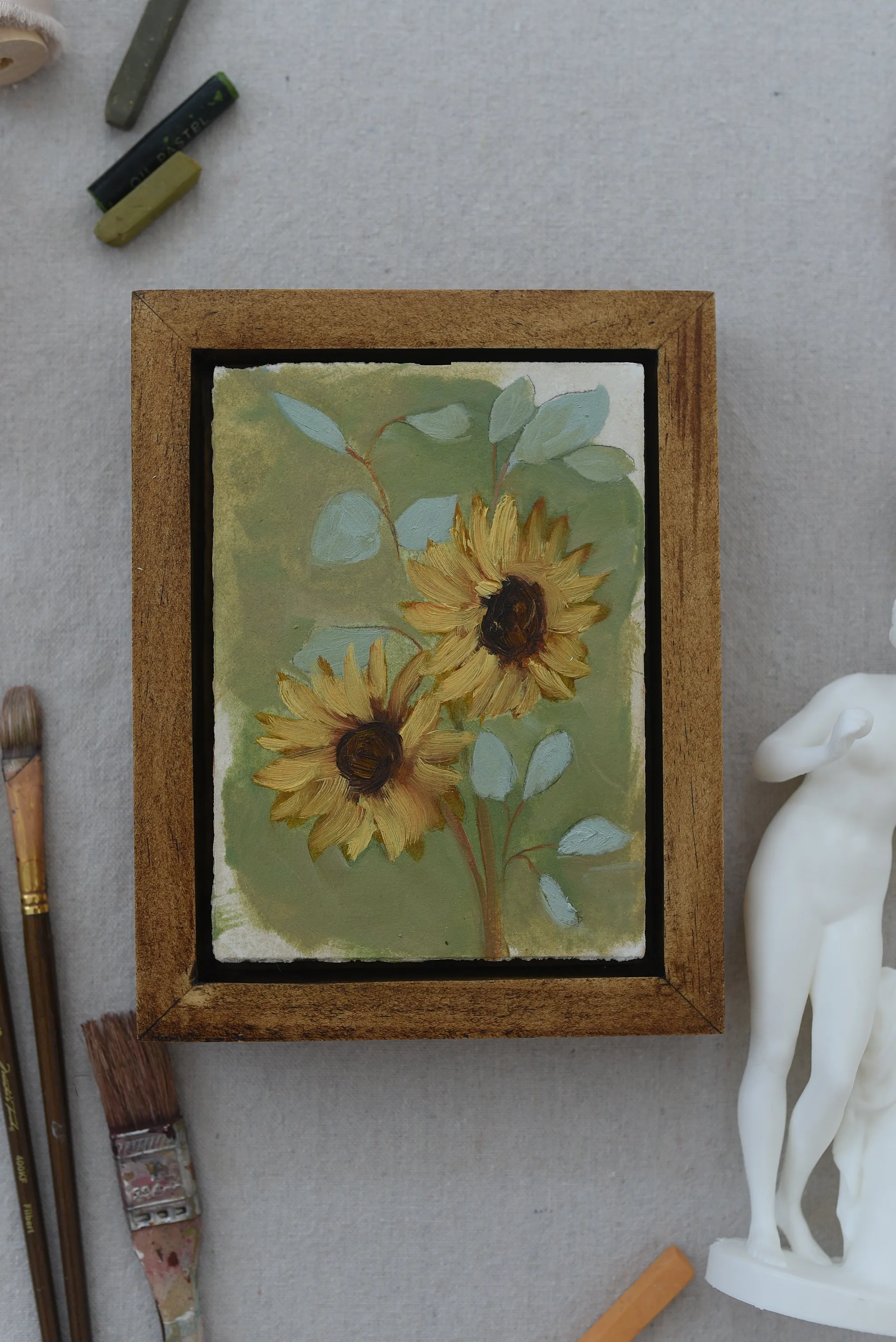 Harmony Bloom, view 11 of 12: three sunflowers radiating warmth against a light green backdrop, interwoven with delicate eucalyptus.