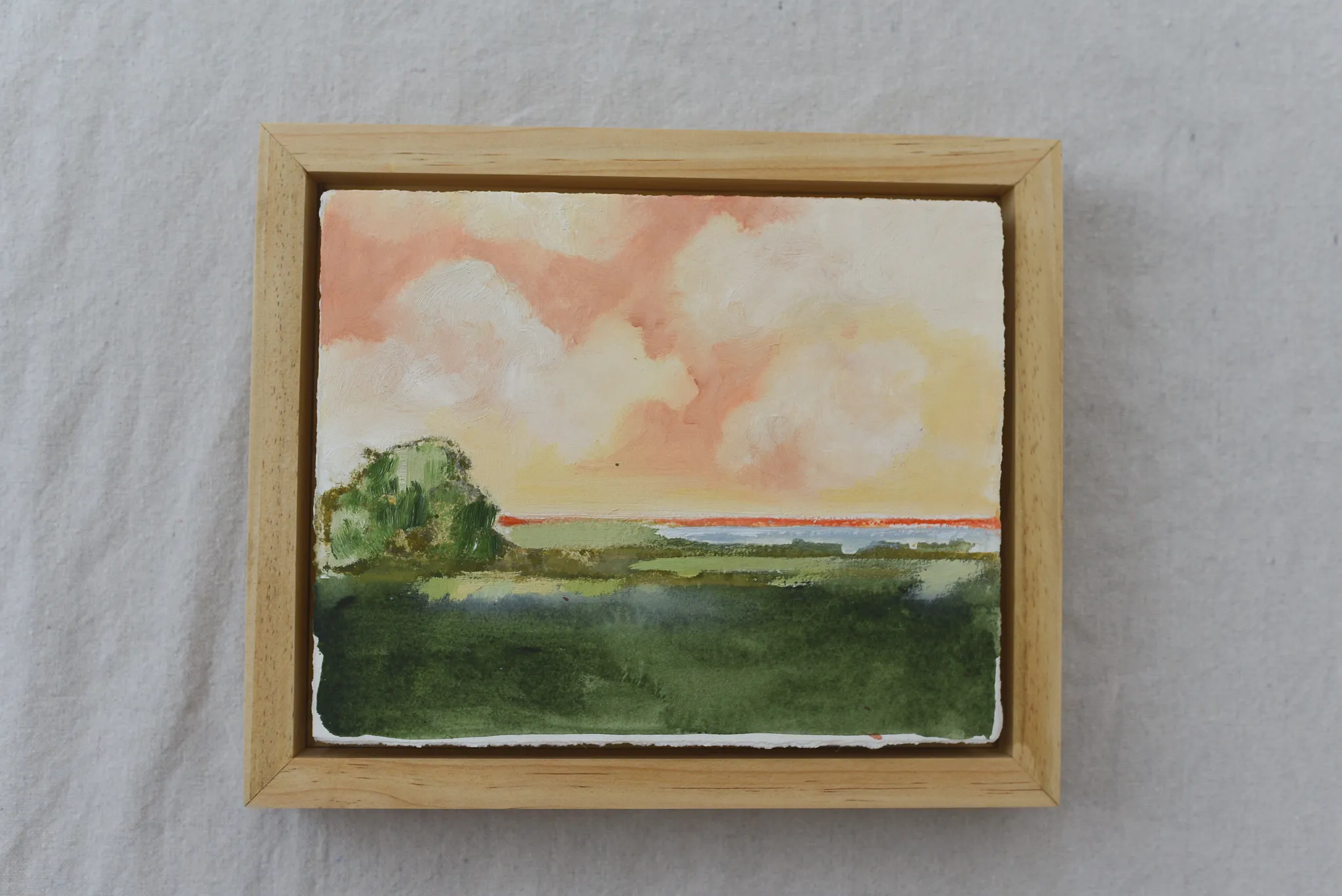 **Hope Horizon** presents a vibrant landscape where warm, puffy clouds painted in soft peaches and radiant yellows dance across the sky, casting a golden glow over the lush green.