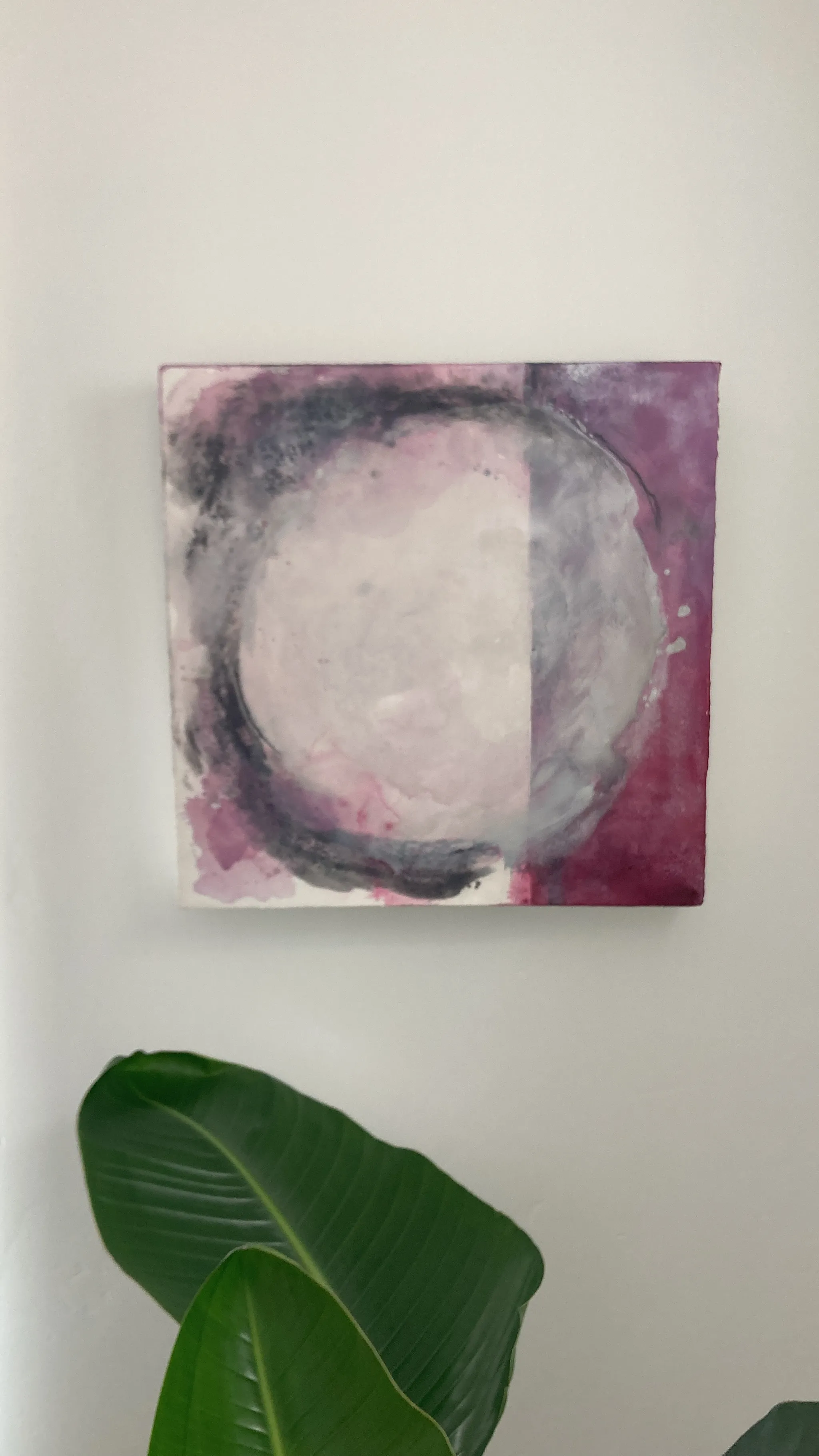 In Between up close on the wall, a silver circle in soft whites and greys, washed with plum at the edges.