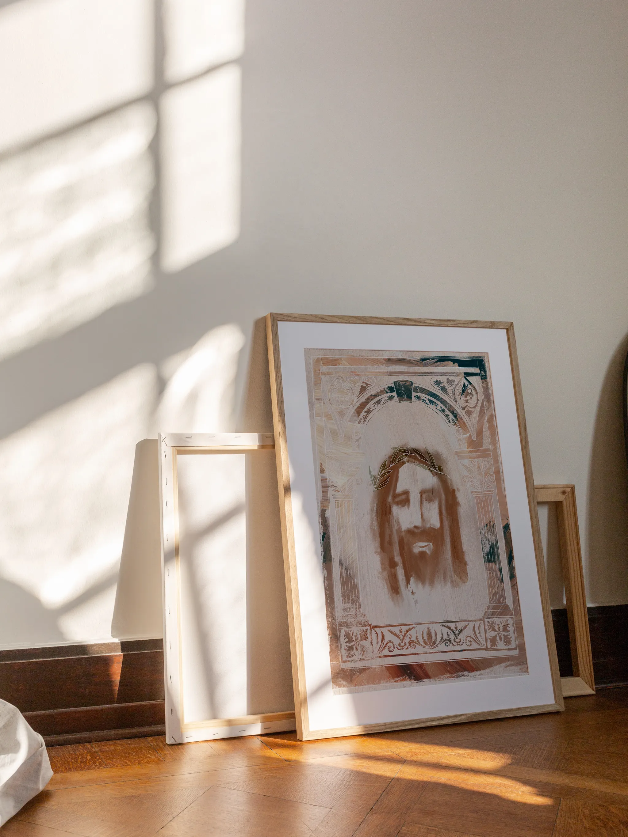 Jesus Crown of Thorns, Art Deco, framed in light wood with a white mat, leaning against a wall on a wooden floor in slanting sunlight, with empty frames behind it.