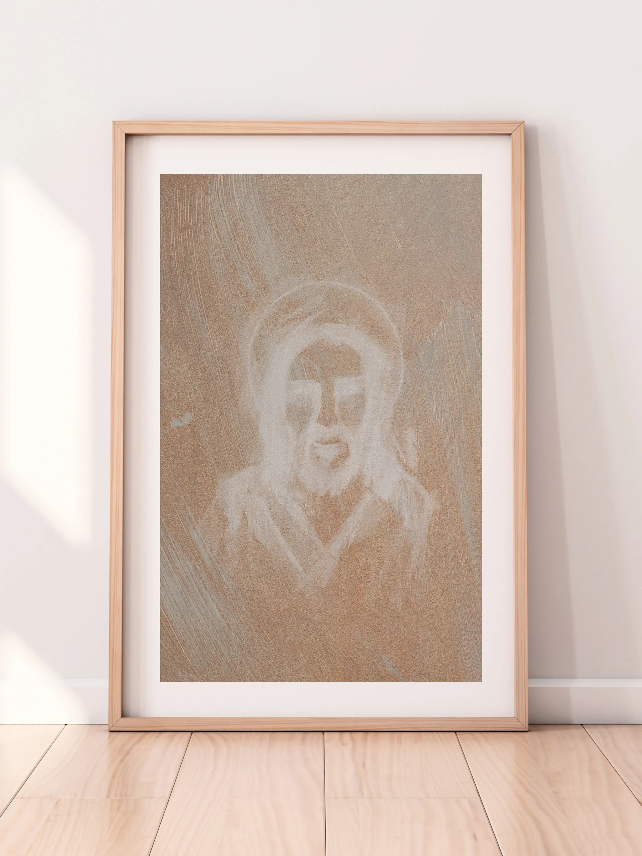 Jesus Portrait, Etched in White, framed in light wood with a white mat, leaning against a pale wall on a light wood floor.