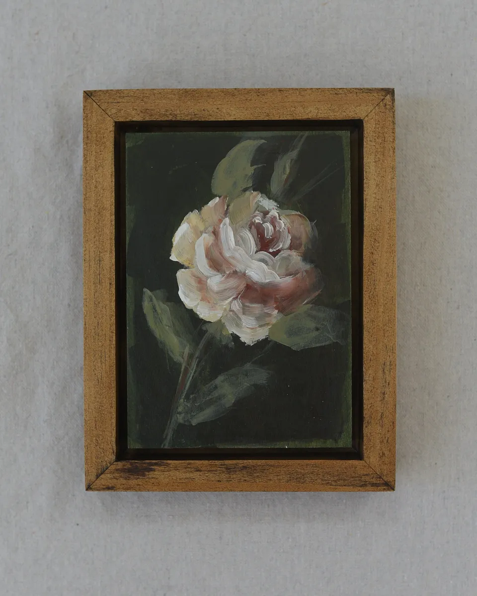 A delicate rose blooms against a dark olive green background, painted in acrylic on raw wood.