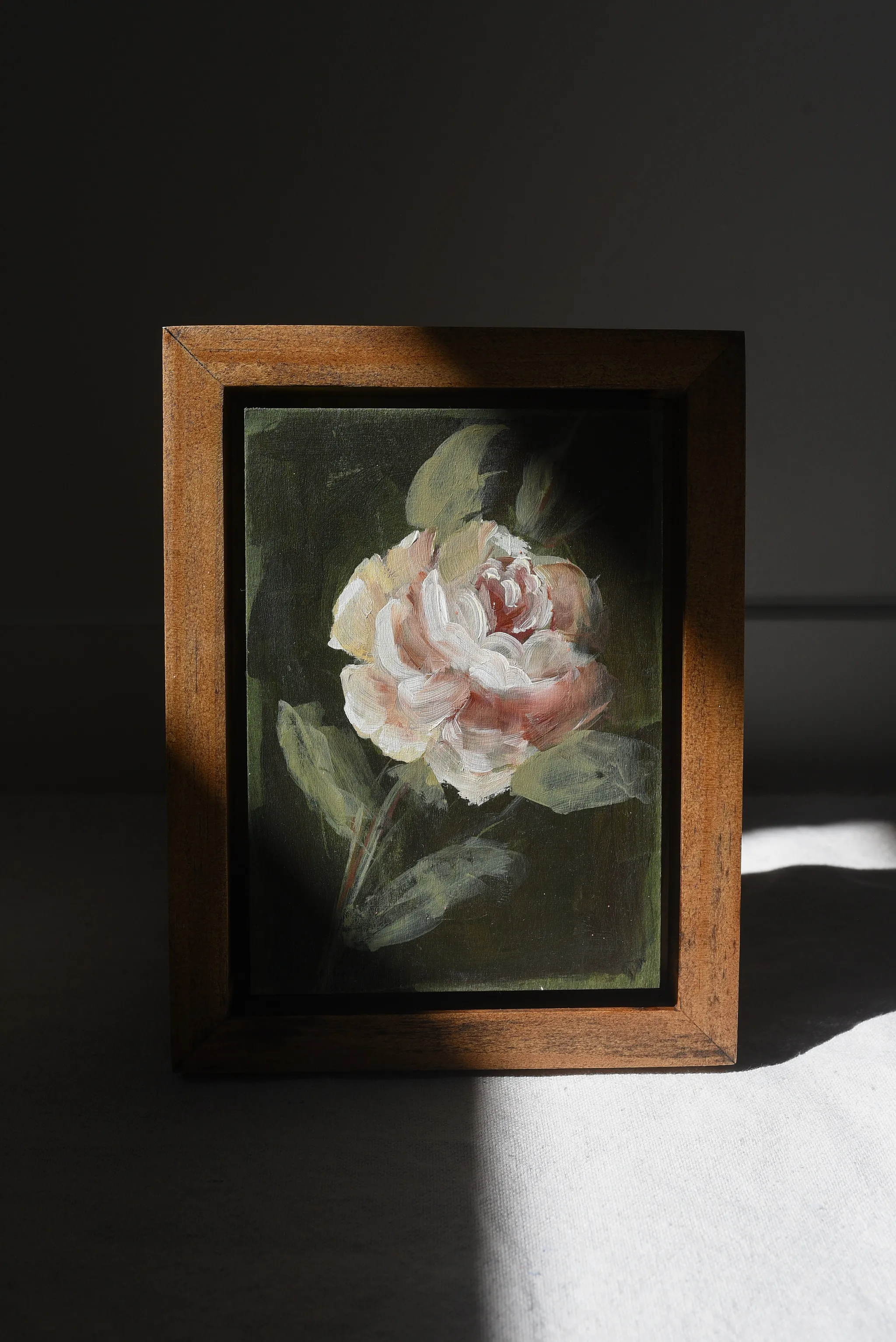 Olive Bloom, view 2 of 5: A delicate rose blooms against a dark olive green background, painted in acrylic on raw wood.