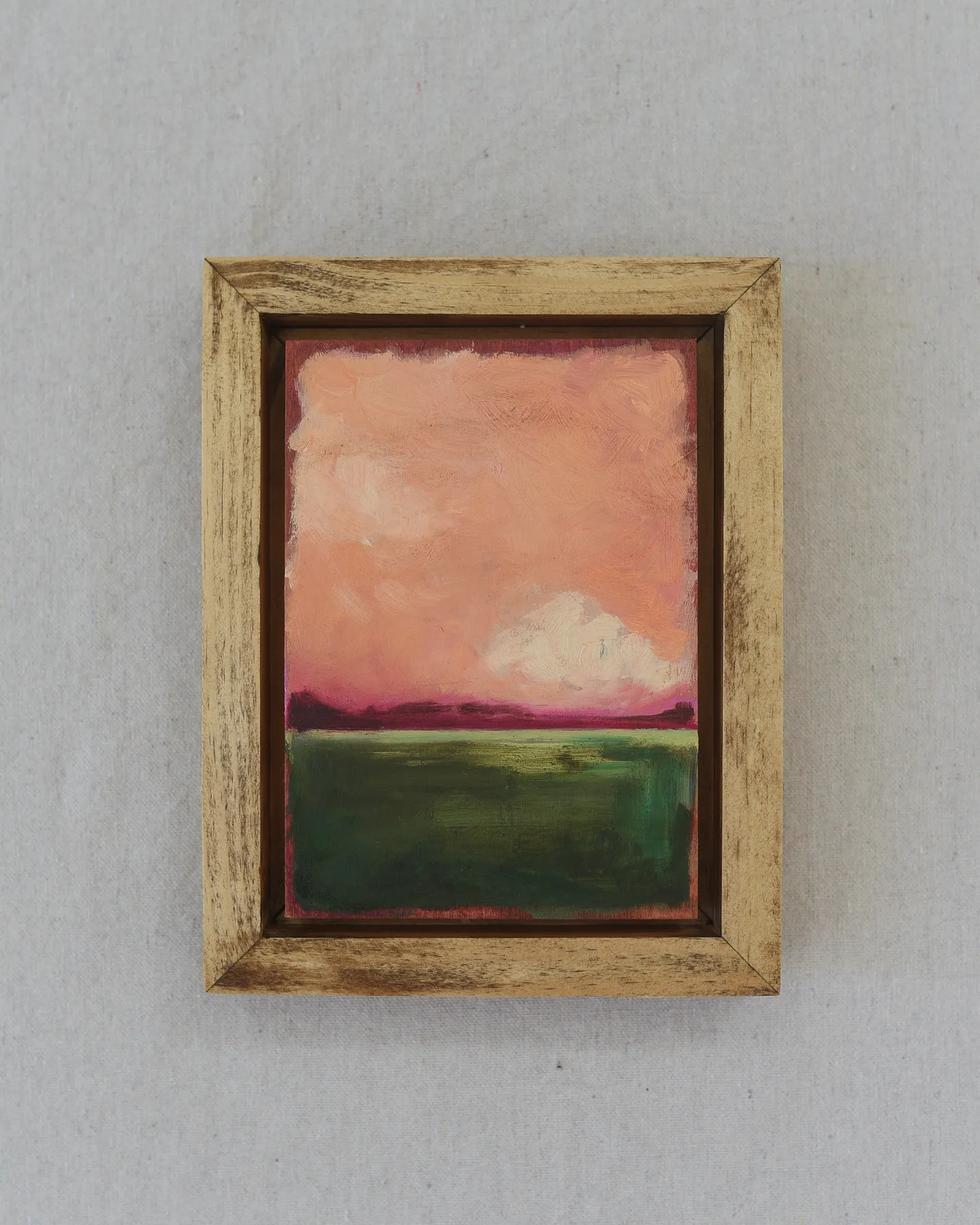 A striking peach and deep magenta sky adorned with soft clouds, set against a backdrop of deep lush green.