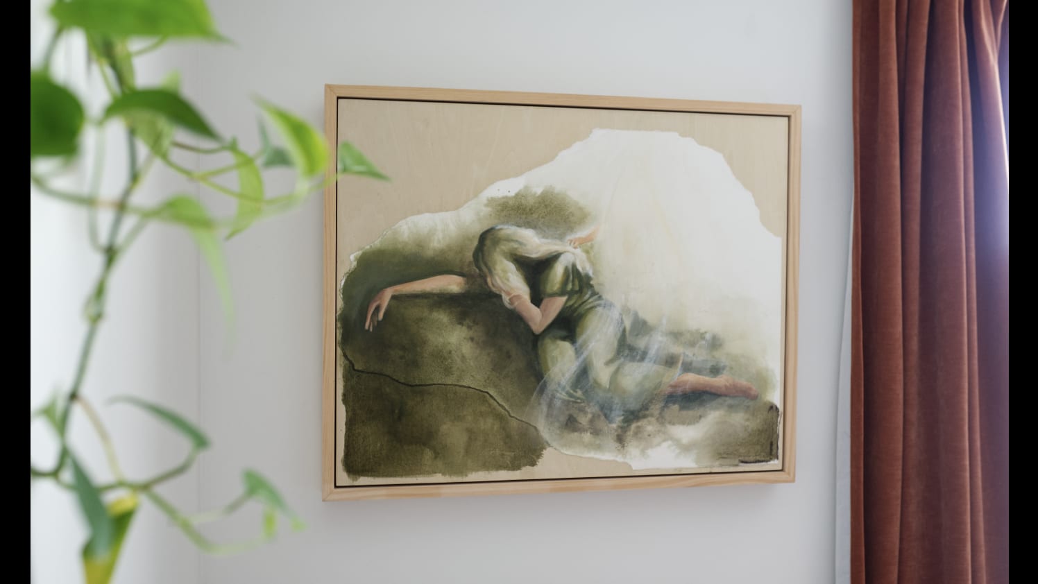 The Motherhood Collection. A Mother's Gethsemane framed in raw wood on a white wall, with a trailing green plant at one side and a deep terracotta curtain at the other.